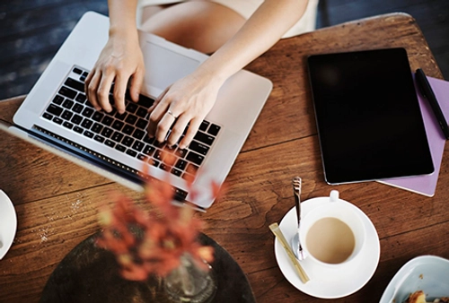 Birds-eye view of hands at a laptop keyboard.