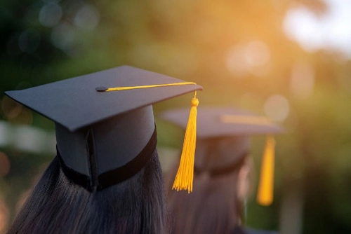 Photo of people in graduation caps facing the sunlight.