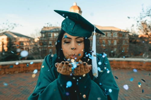 Image of a graduate person blowing petals from her hands