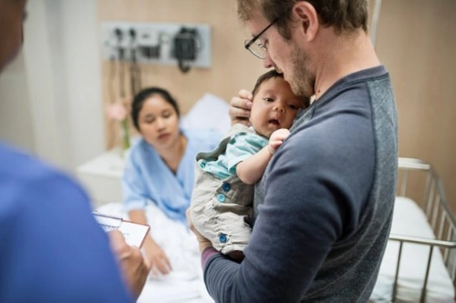 Father holding newborn in neonatal ward