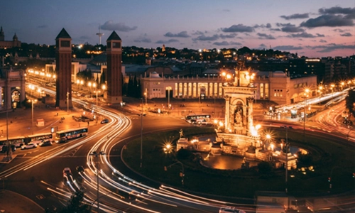 Picture of a street by night, with lit-up lanterns and lit-up old buildings made from stone, that are from a key spanish city.
