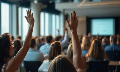 A group of people raising their hands to answer a question
