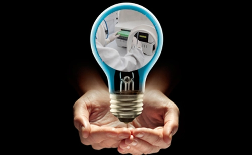 two palms holding lightbulb with a scientist and machinery at the centre