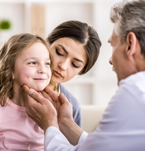 doctor feeling a childs neck glands with mother present