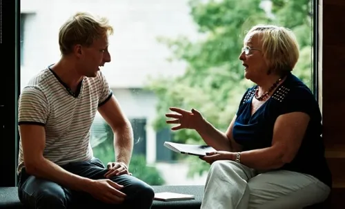 A young man and an elderly woman chatting in the frame of a window