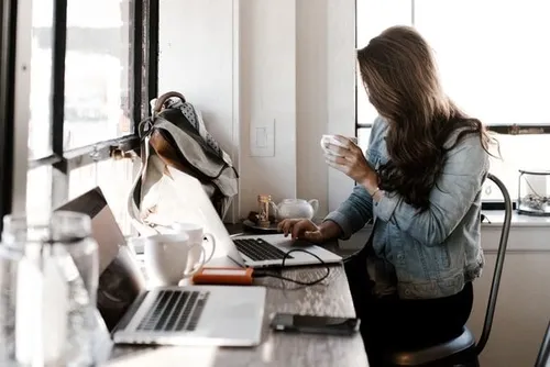 Woman drinking coffee at laptop