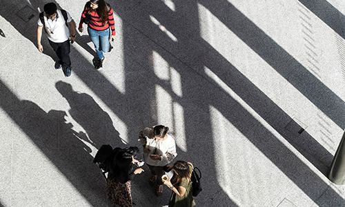 Aerial view of 5 students walking on a concrete walkway