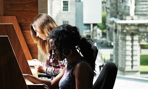Students sitting at Long room hub library desks