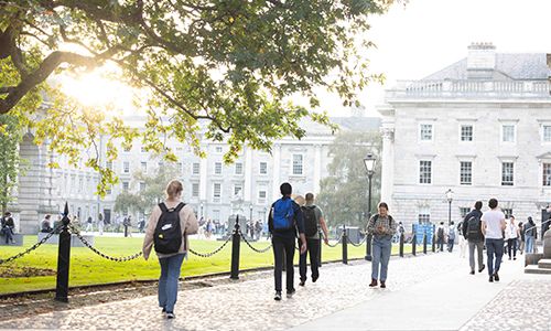 People walking along a leafy campus path