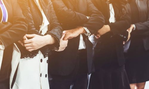 A group of graduates wearing their gowns linking arms