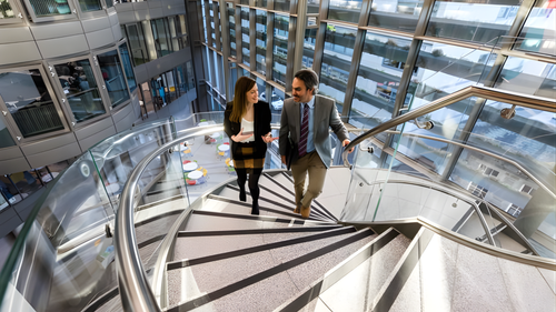 Two education professionals walking up a spiral staircase
