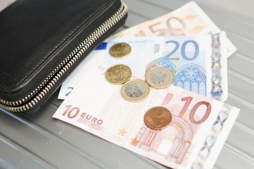 Various notes on a table with coins on top