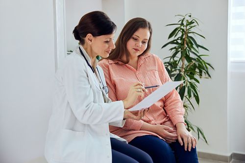 Female doc holding a file and speaking to a pregnant woman