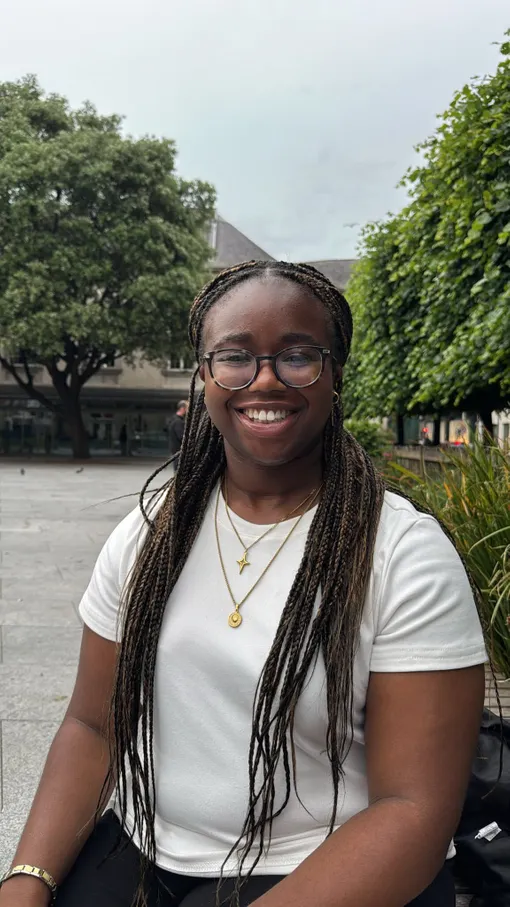 Student with long brown/black hair in braids wearing glasses.
