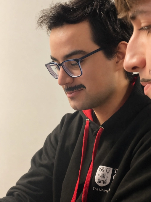Student with short dark hair and a moustache
