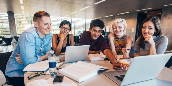 Group of students around a table working on laptops