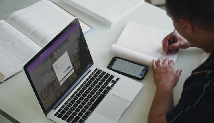 Student working at laptop, taking notes.