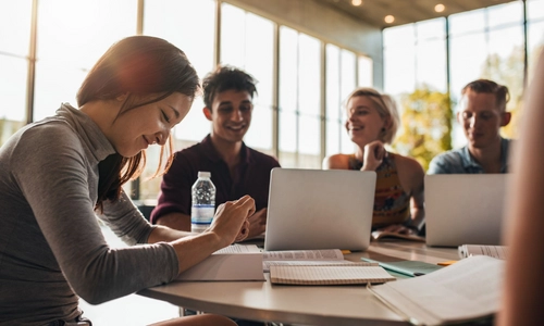 A group of 3 students sitting around a table looking at a computer screen