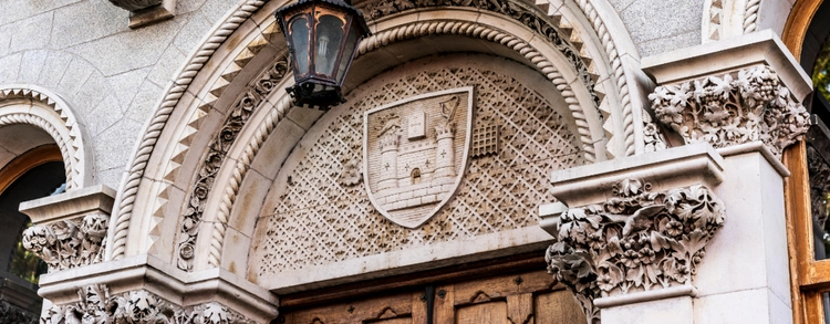 A close up image of the arch over the door of the Museum Building in Trinity College Dublin. The arch has an an engraving of Trinity's crest on it