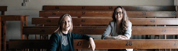 Two women sitting at a row of tiered desks