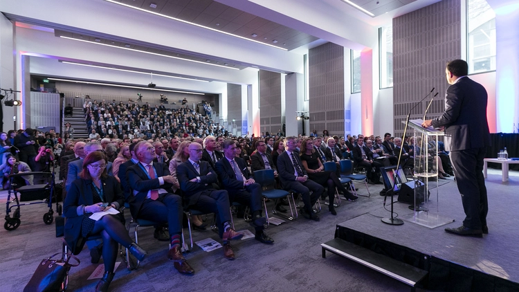 Image of a conference with a big audience and a speaker