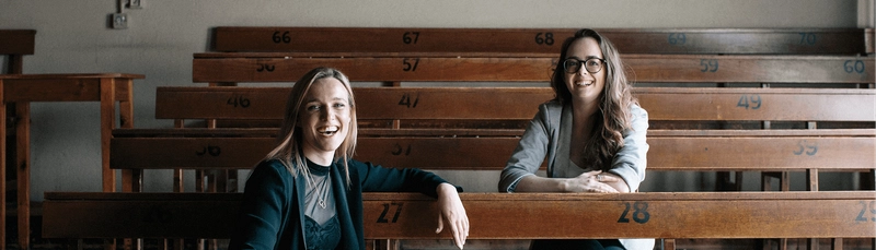 Two women sitting at a row of tiered desks