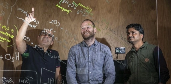 Scientists and engineers working on a transparent whiteboard