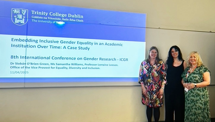 three women standing next to presentation screen