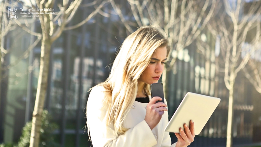 Person holding notepad and phone, looking at notepad and speaking into the phone.