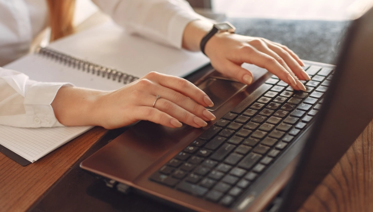 Hands typing on laptop keyboard