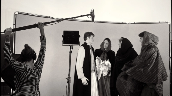 A group of Trinity students wearing historical dress on a film set.