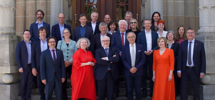 Large group of people standing on the steps of a building, all smiling for the camera.