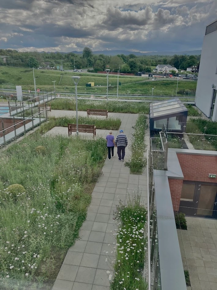 Two older people walking in a rooftop garden in a RLTC setting