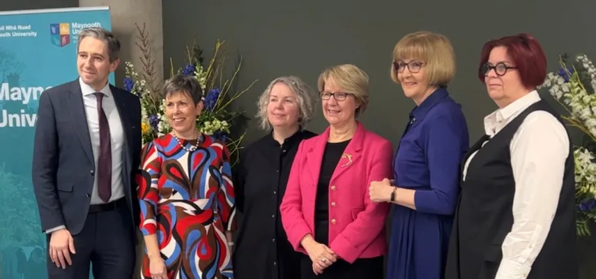 Group of six people standing for a photo. They are looking at a camera towards the left of the frame.