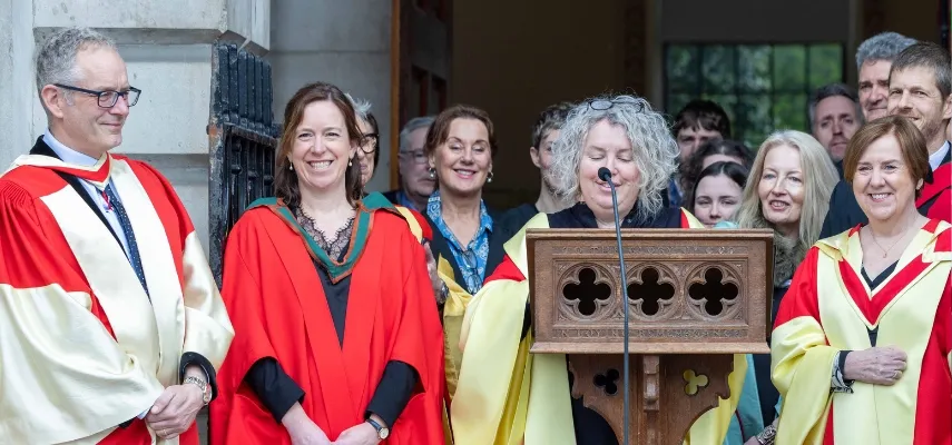 Linda announcing Trinity scholars on the steps of Public Theatre. She is surrounded by college officers, all wearing academic robes and smiling.