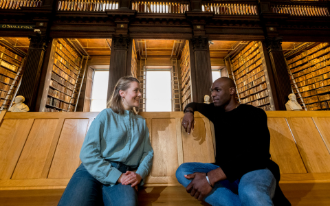 Two students seated in Trinity's Old Library.