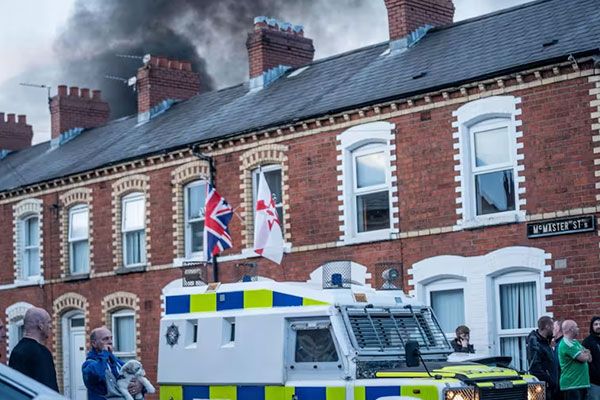 Image of Police van and burning house in Belfast.