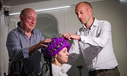 Image of two people putting the new OPM-MEG scanner on another person.