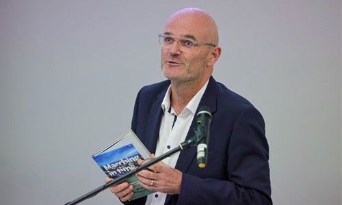 Image of Professor Laurent Muzellec holding the published history of the Trinity Business School.