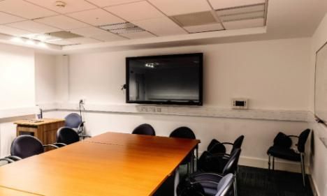 Room b1.06.2 in TBSI. This room has a large conference table and chairs in it and a large monitor on the wall
