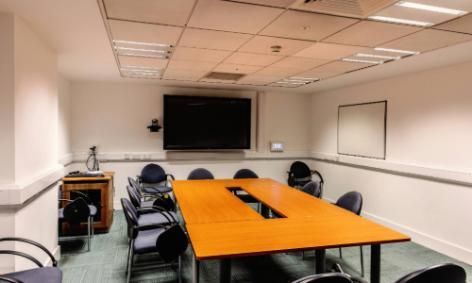 Room b1.18 in TBSI, This room has a large conference table and chairs in it and a large monitor on the wall