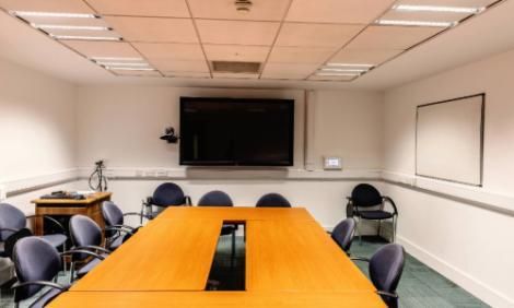 Room b1.18.2 in TBSI. This room has a large conference table and chairs in it with a large monitor on the wall