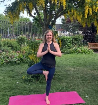 Figure balancing on one leg on yoga met in Trinity rose garden.