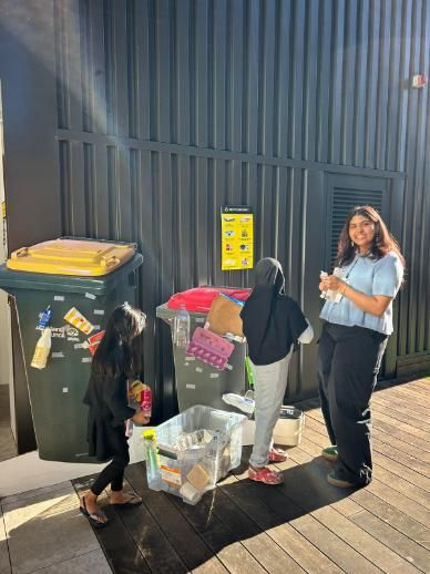 Student standing beside recycling materials whilst volunteering