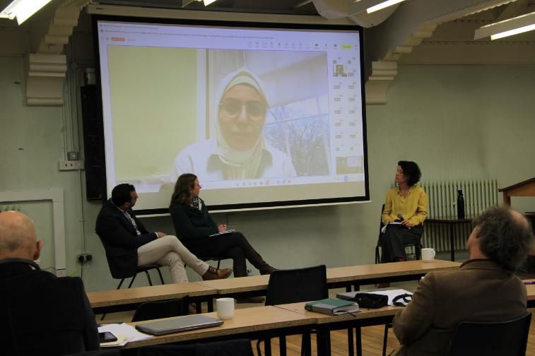An image of three people presenting with another on screen
