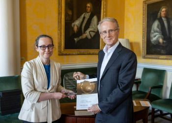 Two people standing beside each other holding a award made from glass