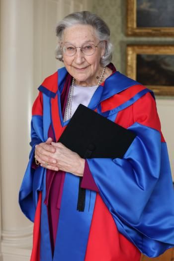 Corinna Salvadori Lonergan wearing ceremonial robes holding her Honorary Degree.