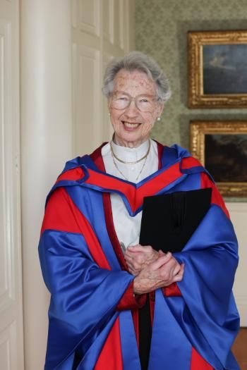 Eda Sagarra wearing ceremonial robes holding her Honorary Degree.