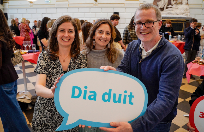 Attendees at the Languages Alumni Summer Social in the Exam Hall on 5 June 2026 holding a 'Dia Duit' sign.