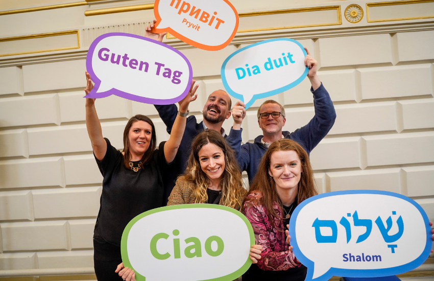 Attendees holding signs with greetings in all the languages taught in the School of Languages, Literatures and Cultural Studies.